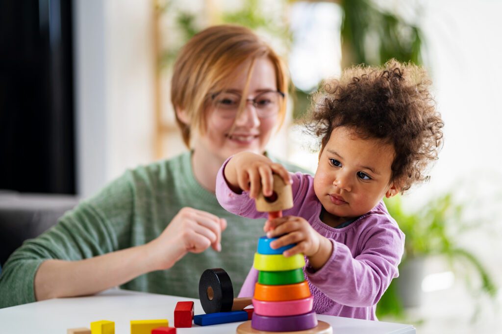 Mother looking at a child playing with an educational toy